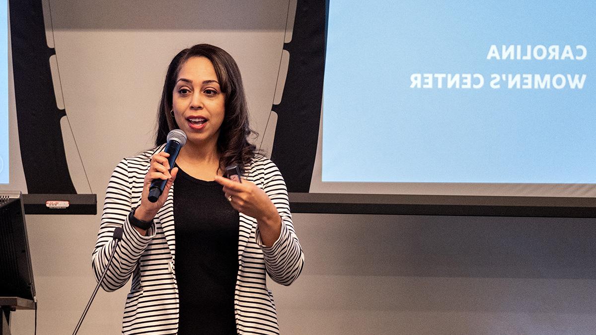 Shauna Harris speaking in front of screen that reads 